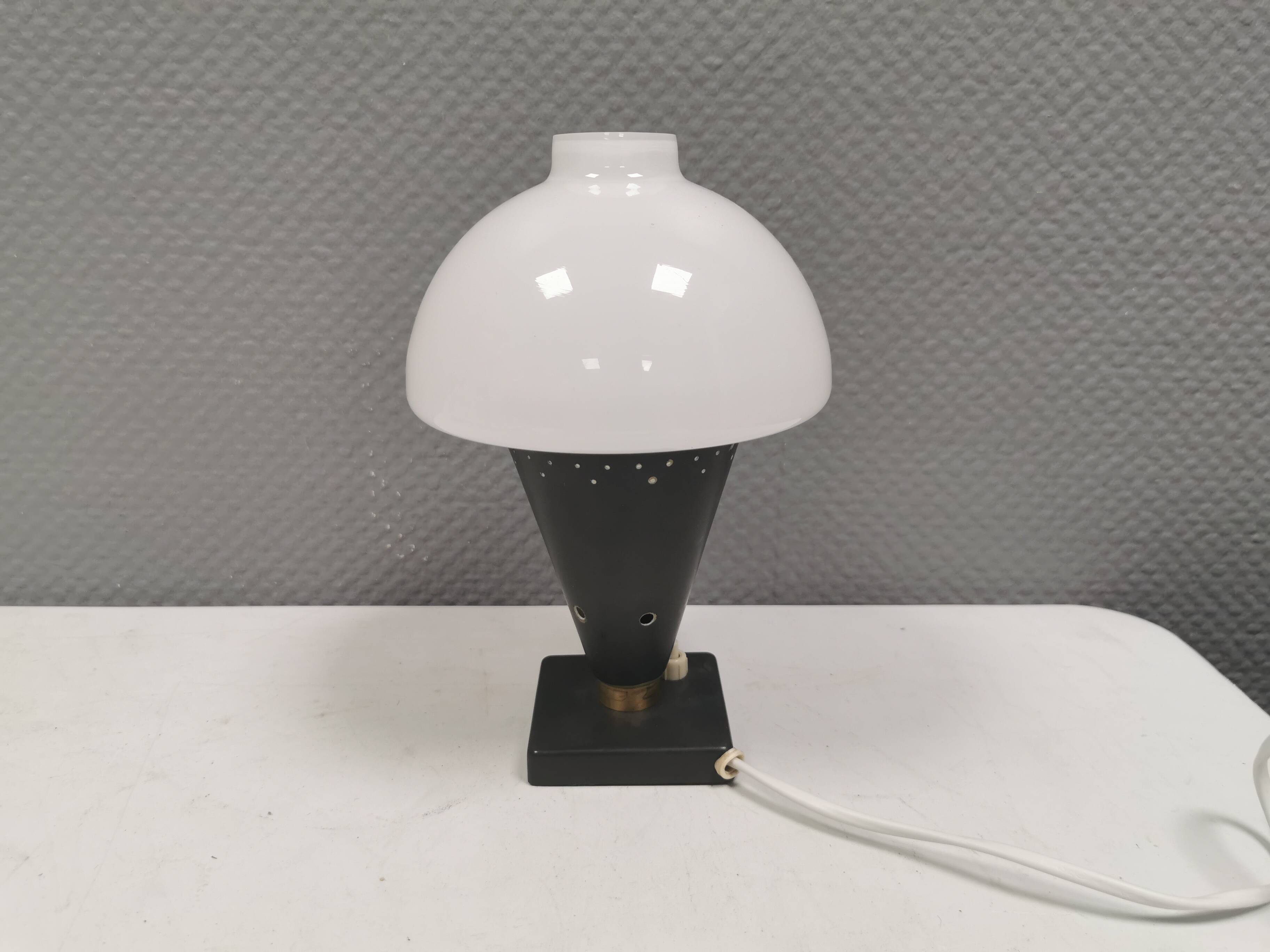 Small stylish table lamp with perforations and milky white opal glass shade