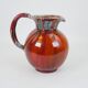 Large red and blue glazed ceramic pitcher signed Delène under the base