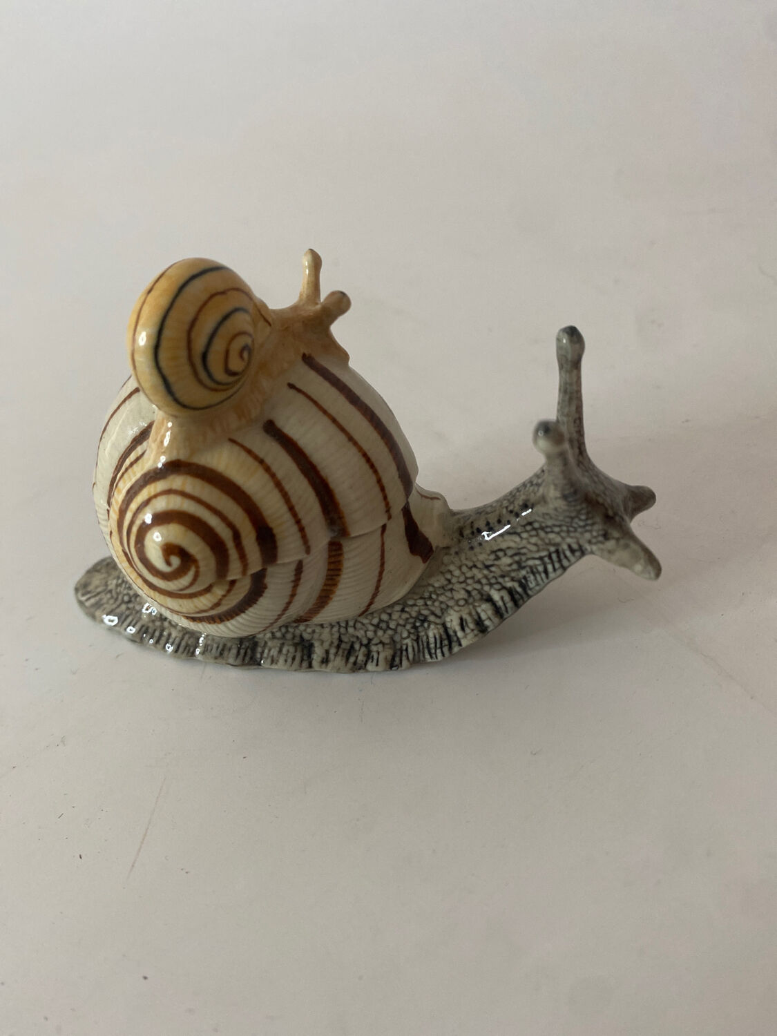 Porcelain figurine snail and its small