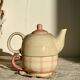 Vintage porcelain teapot and cup set with pink and beige floral and gingham pattern