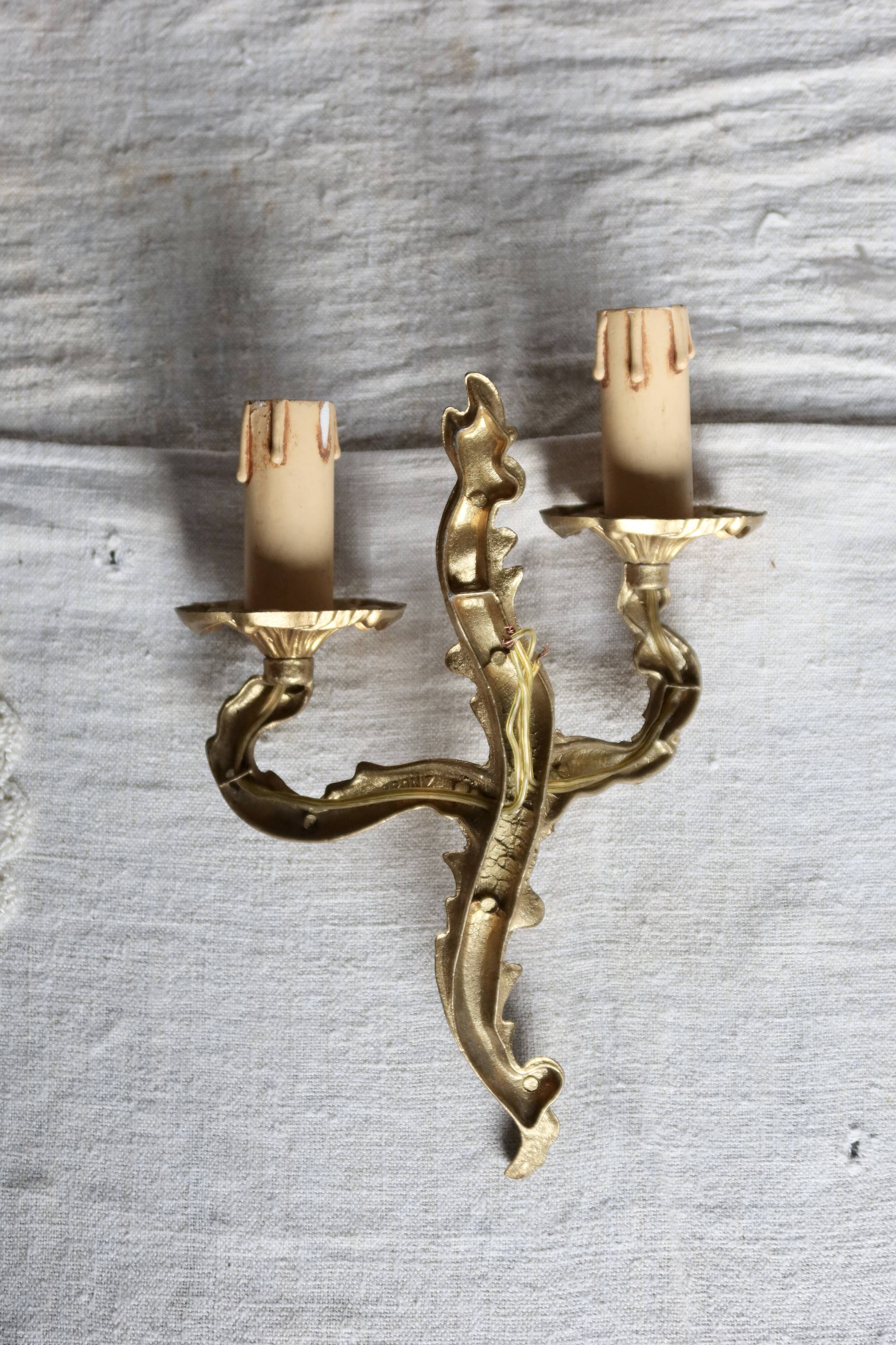 Vintage wall sconce in gold metal with two arms in classic style.