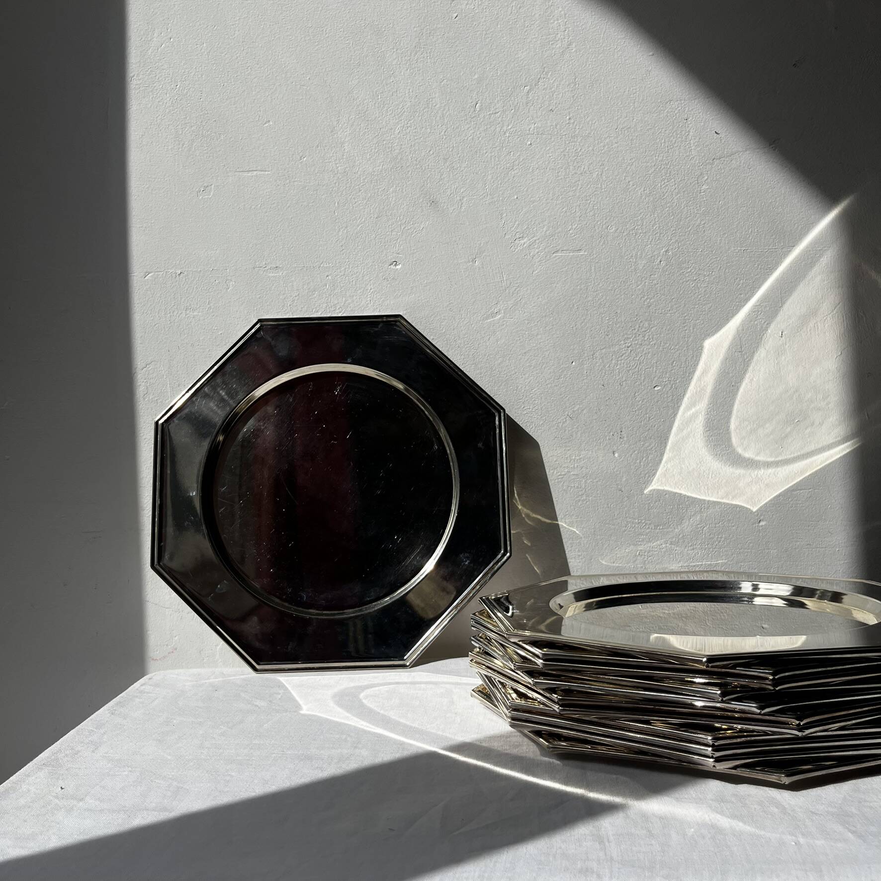 Many octagonal presentation plates in silver-plated metal.