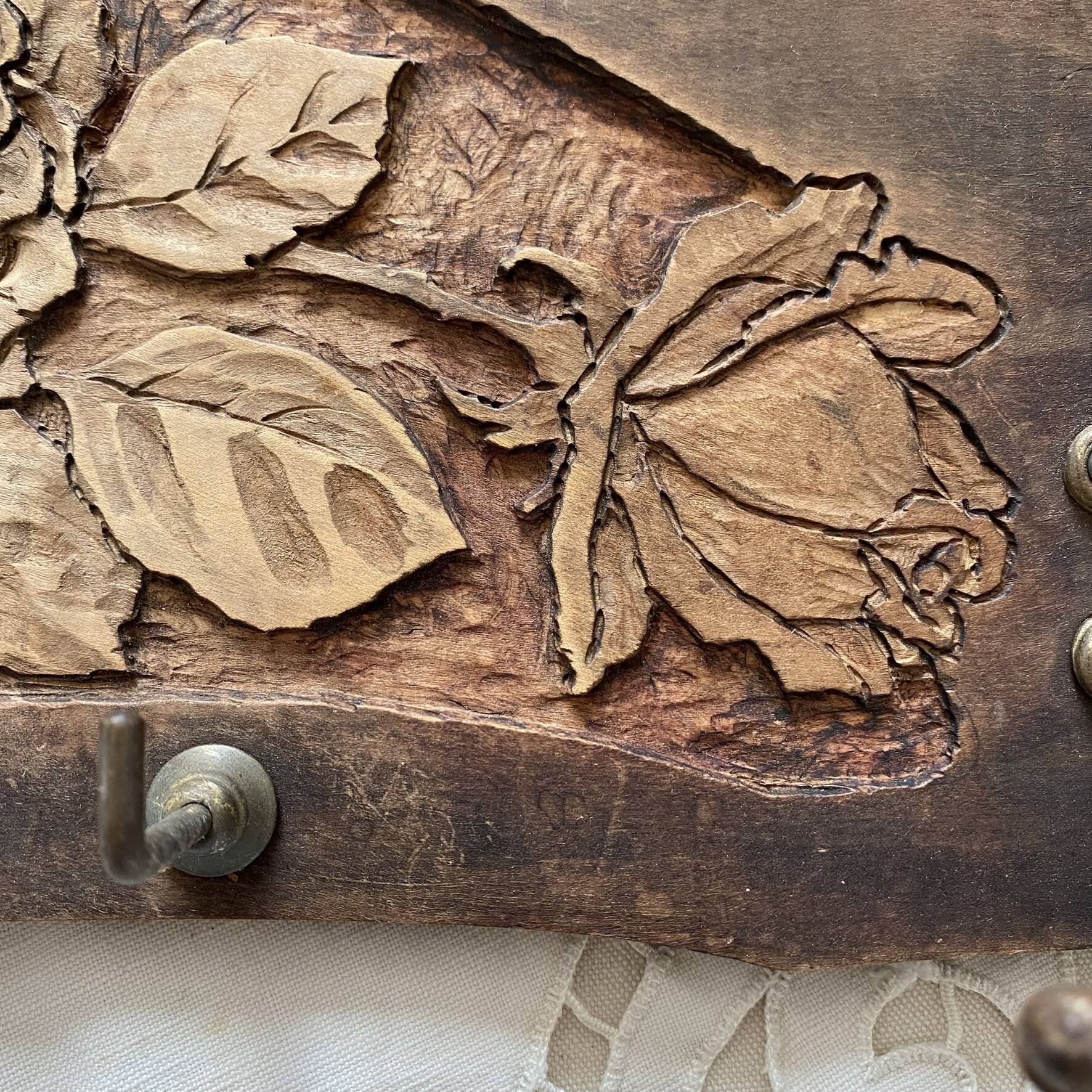 Wall-mounted coat rack in carved wood with rose decoration.