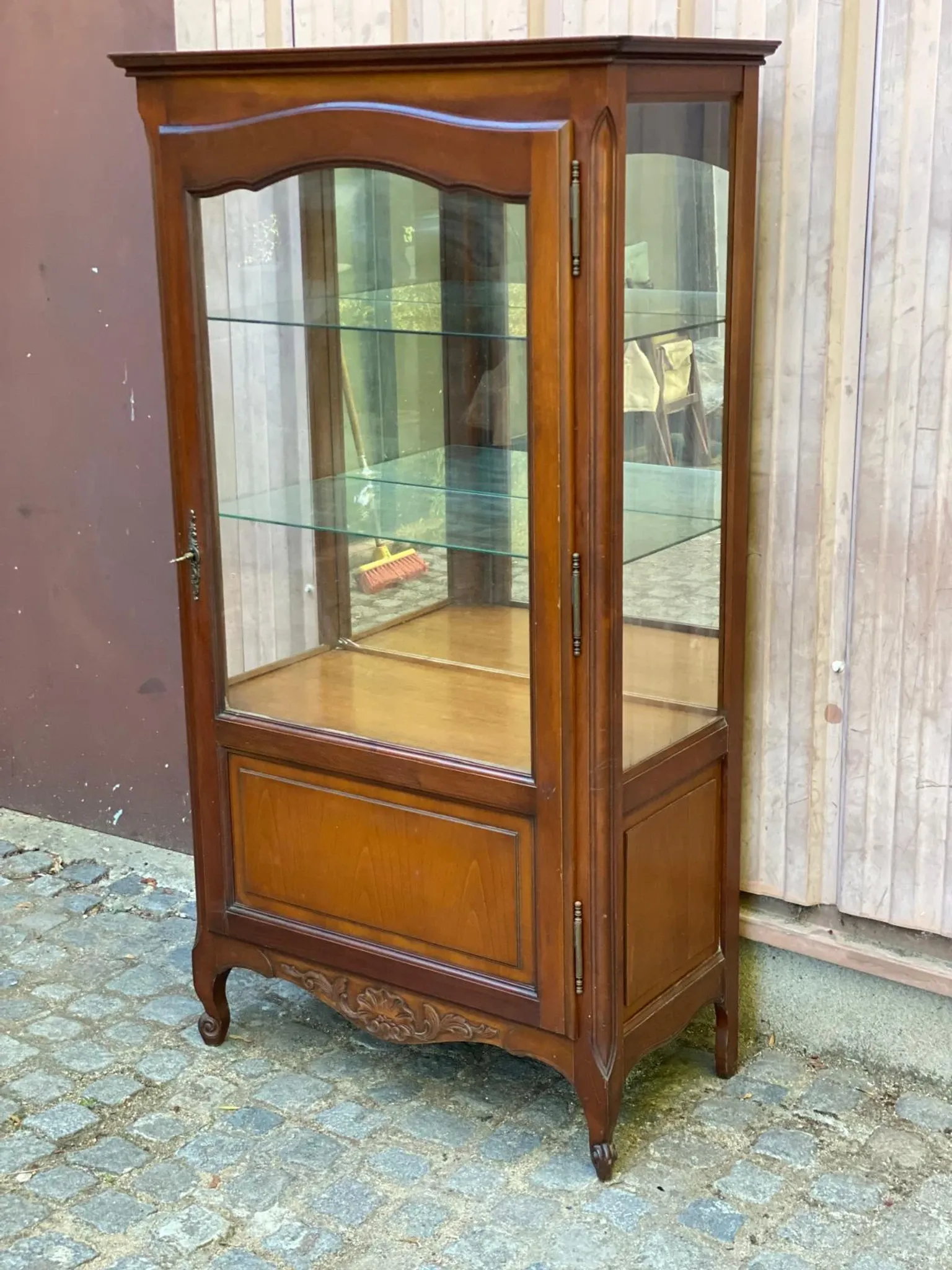 Louis XV style display cabinet in cherry wood with a mirrored back and glass shelves.
