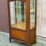 Louis XV style display cabinet in cherry wood with a mirrored back and glass shelves.