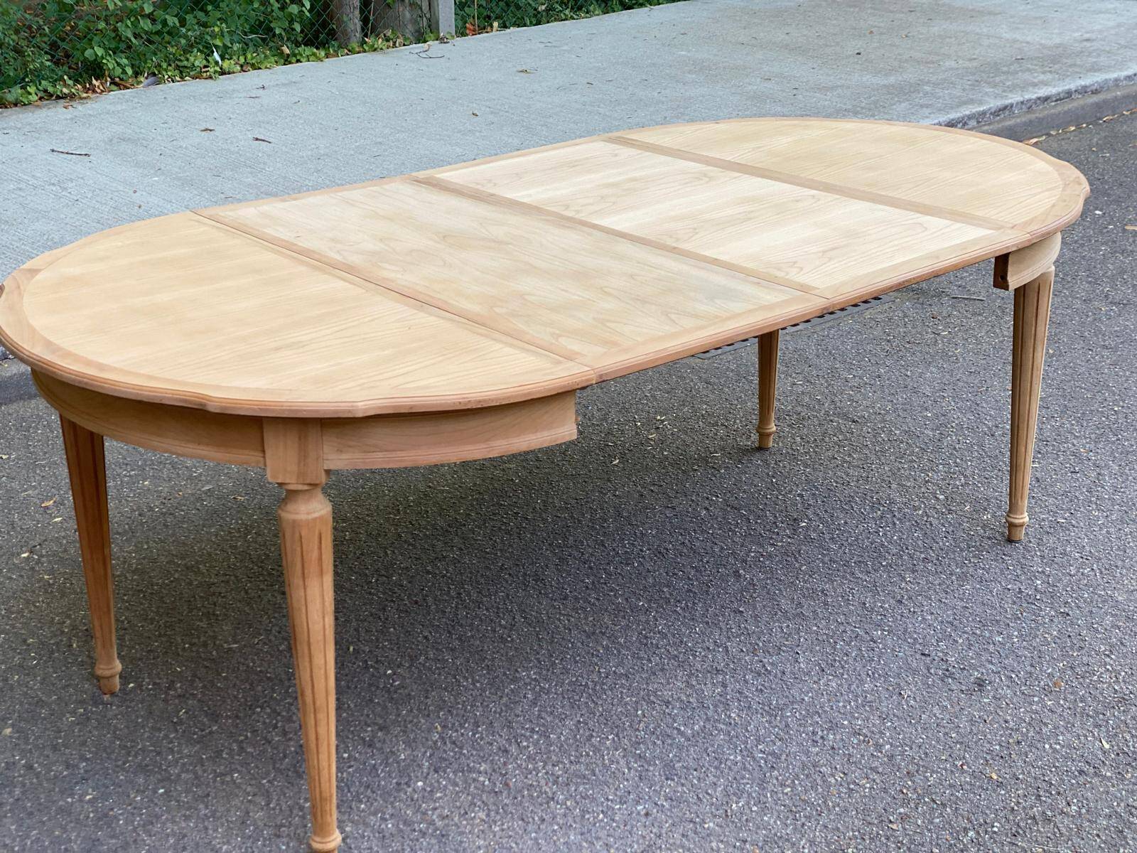 Extendable round table in renovated Louis XVI style, made of light wood, with 2 extensions.