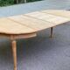Extendable round table in renovated Louis XVI style, made of light wood, with 2 extensions.