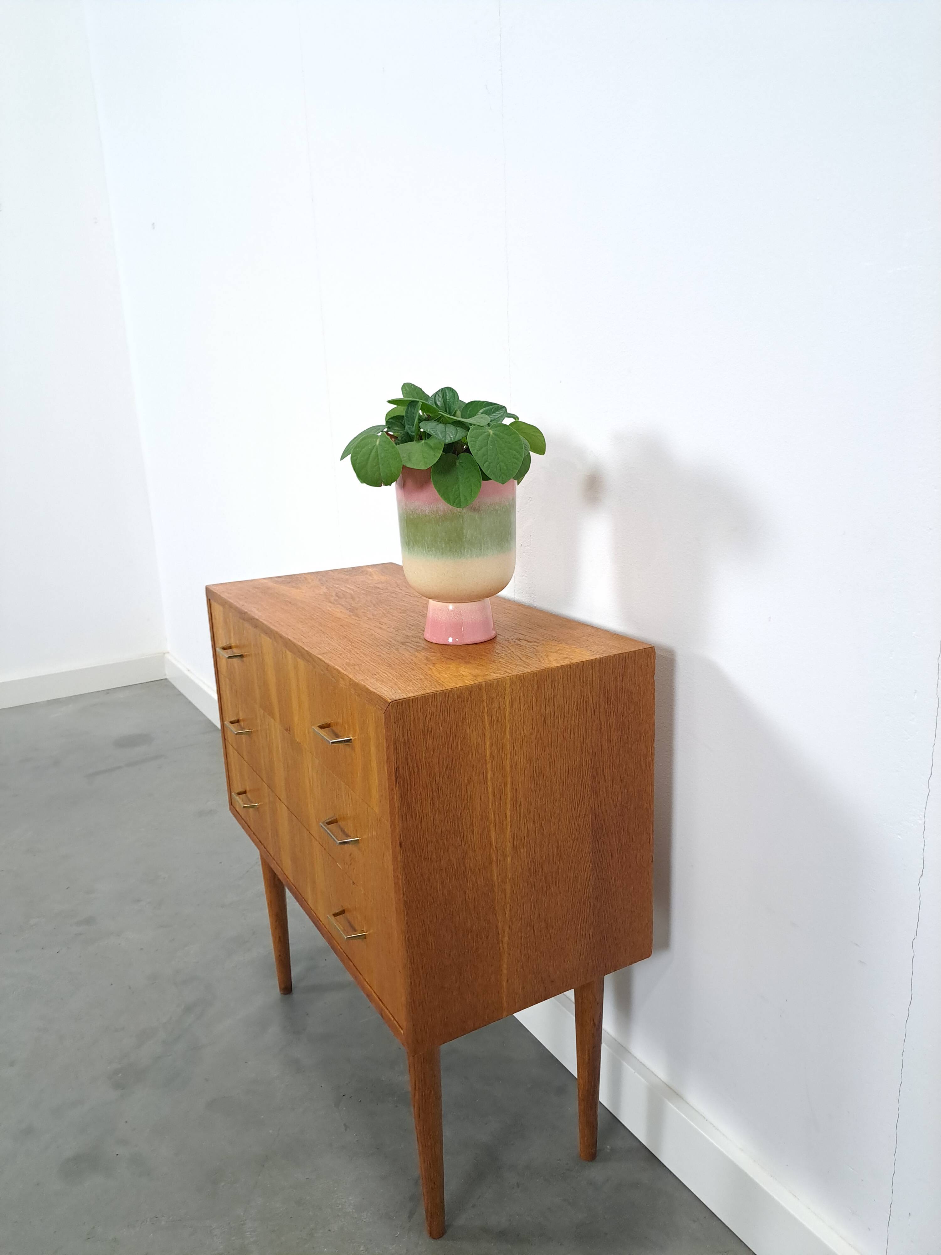 Commode danoise avec de hauts pieds et des poignées dorées.