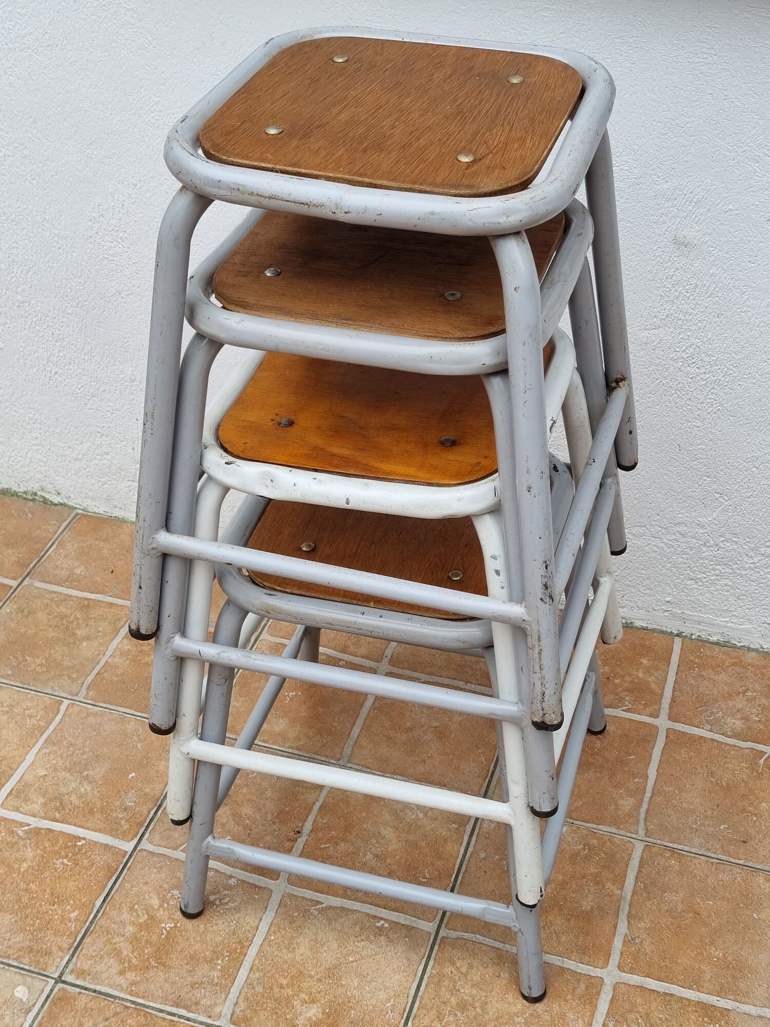 Set of four stackable industrial tubular metal and wood stools