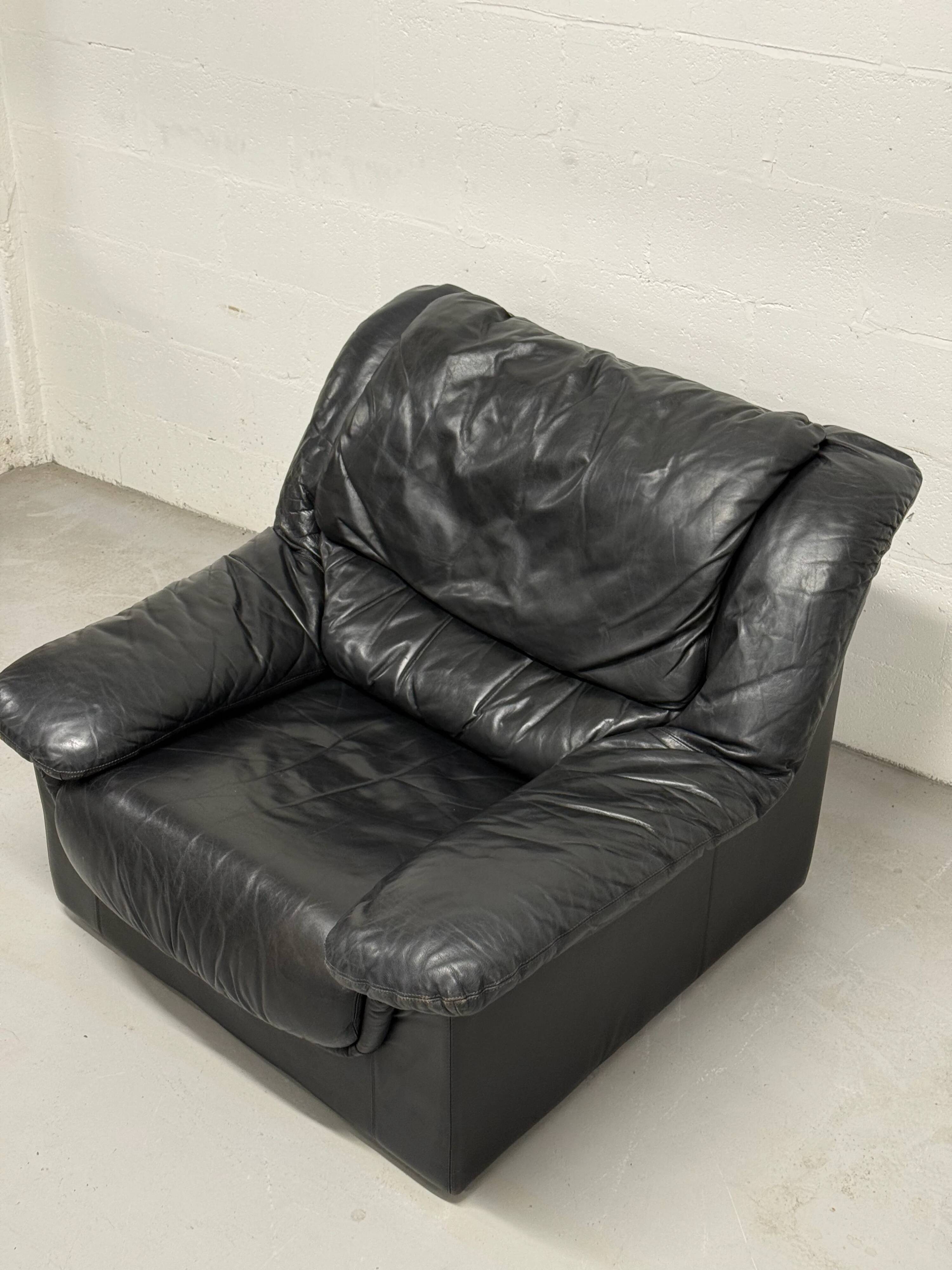 Vintage black leather lounge chair — low postmodern club chair from the space age.