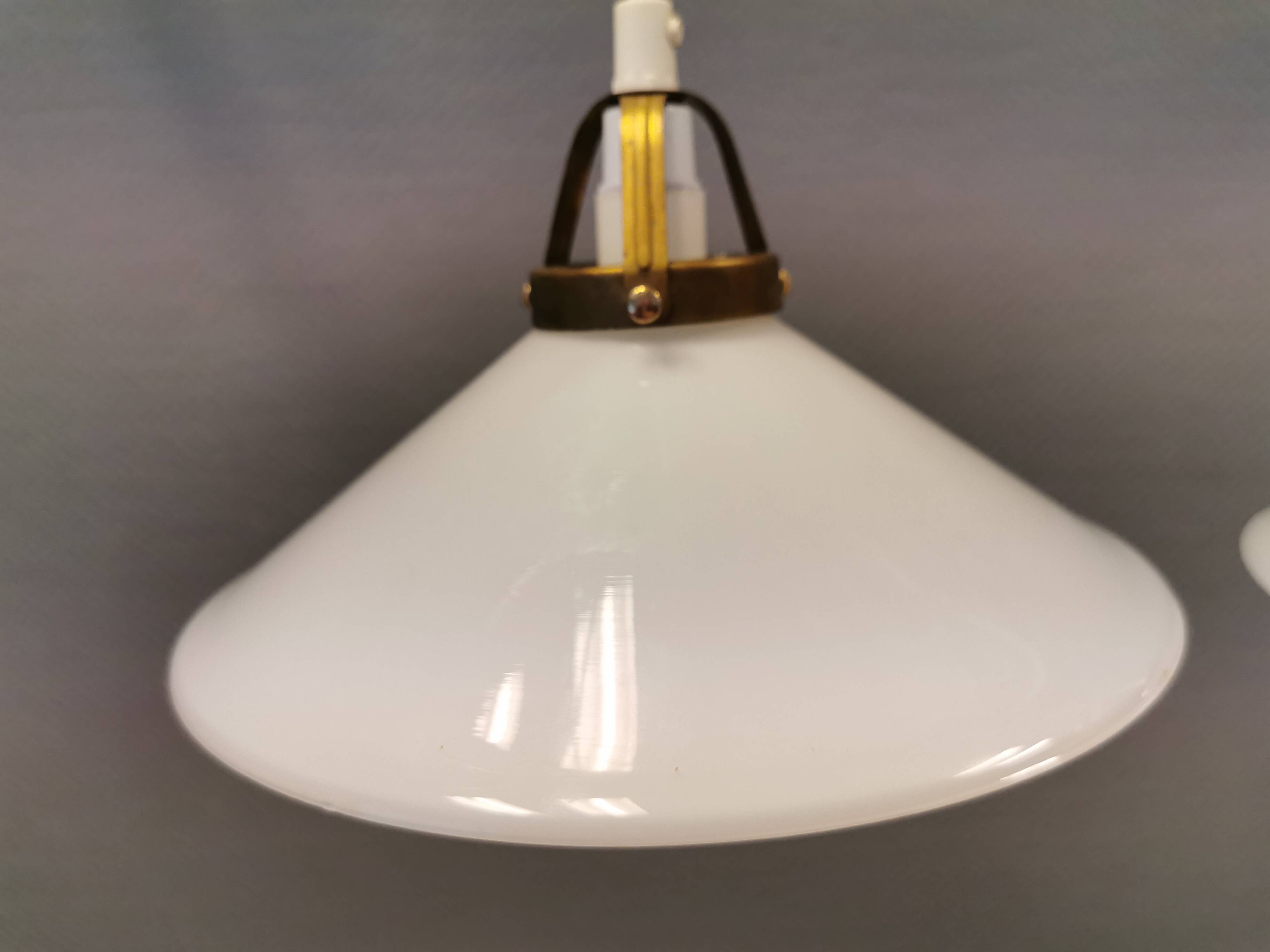 A set of hanging lamps in milky white opal glass with brass top.