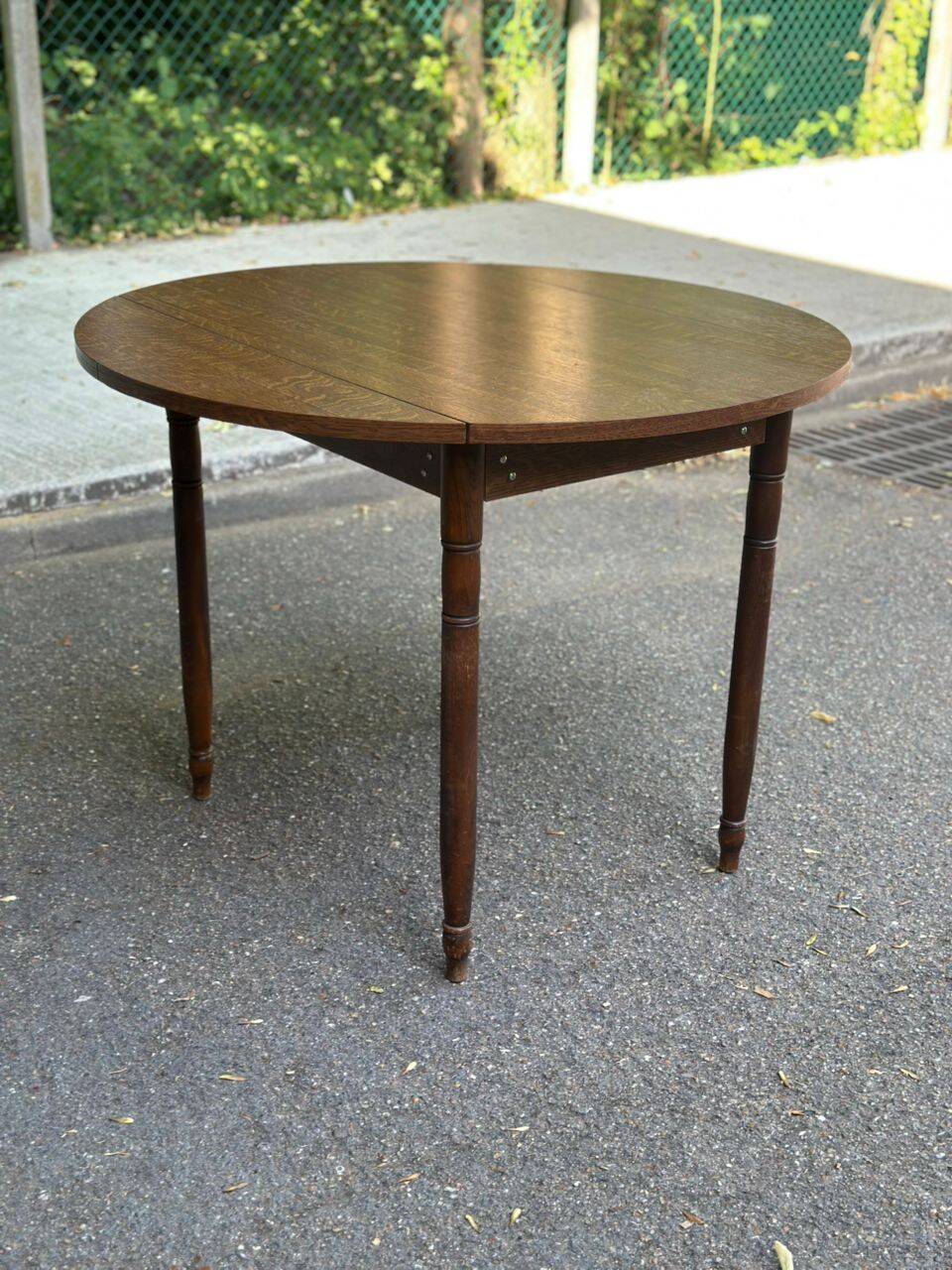 Round kitchen table with extendable leaves in dark wood.