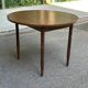 Round kitchen table with extendable leaves in dark wood.