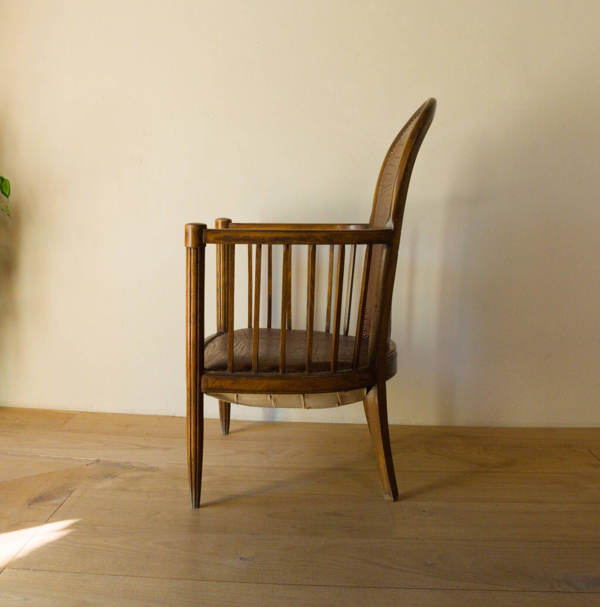 Antique armchair in solid wood and patinated brown leather, early 20th century.