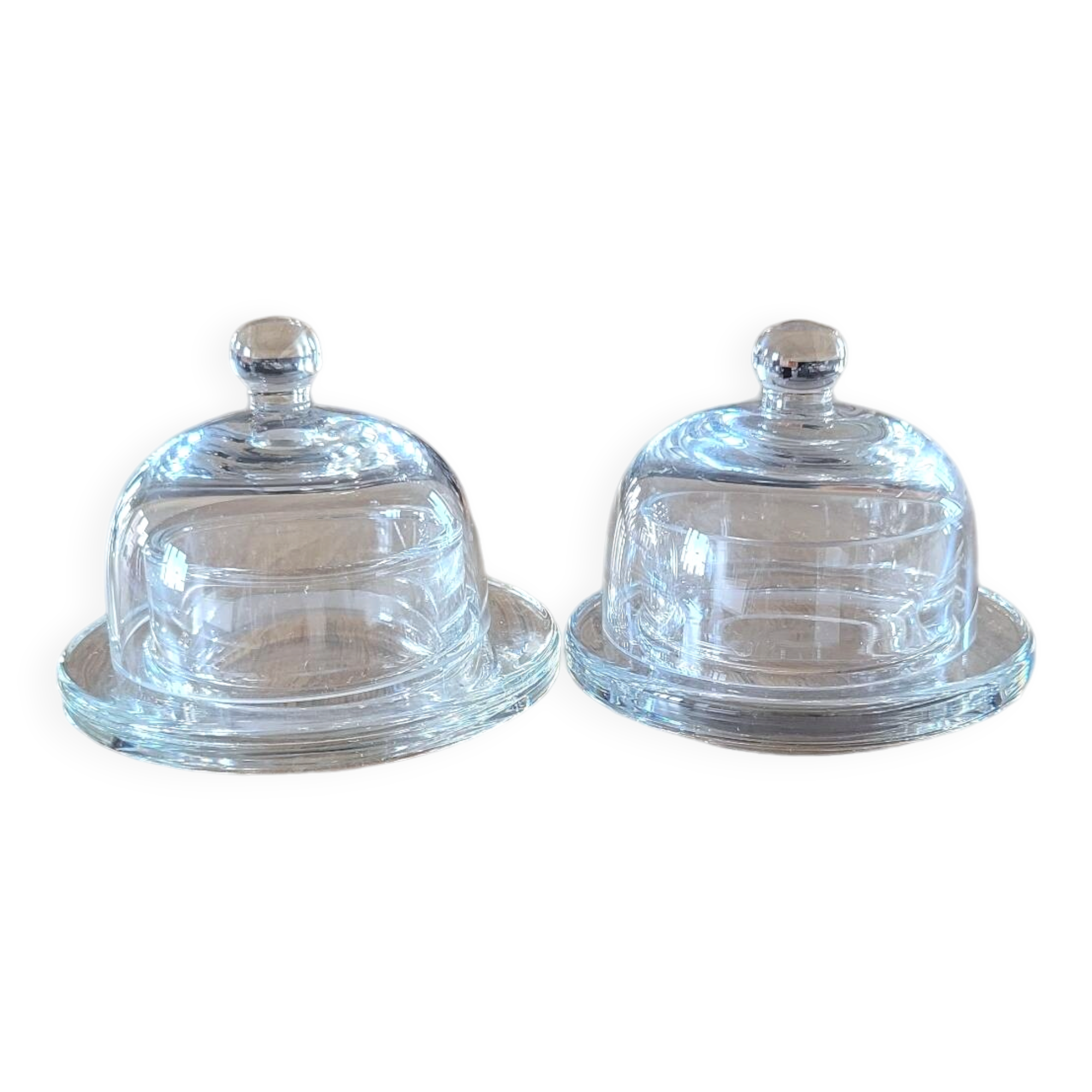2 transparent glass butter dishes with their matching cloches.