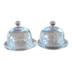 2 transparent glass butter dishes with their matching cloches.