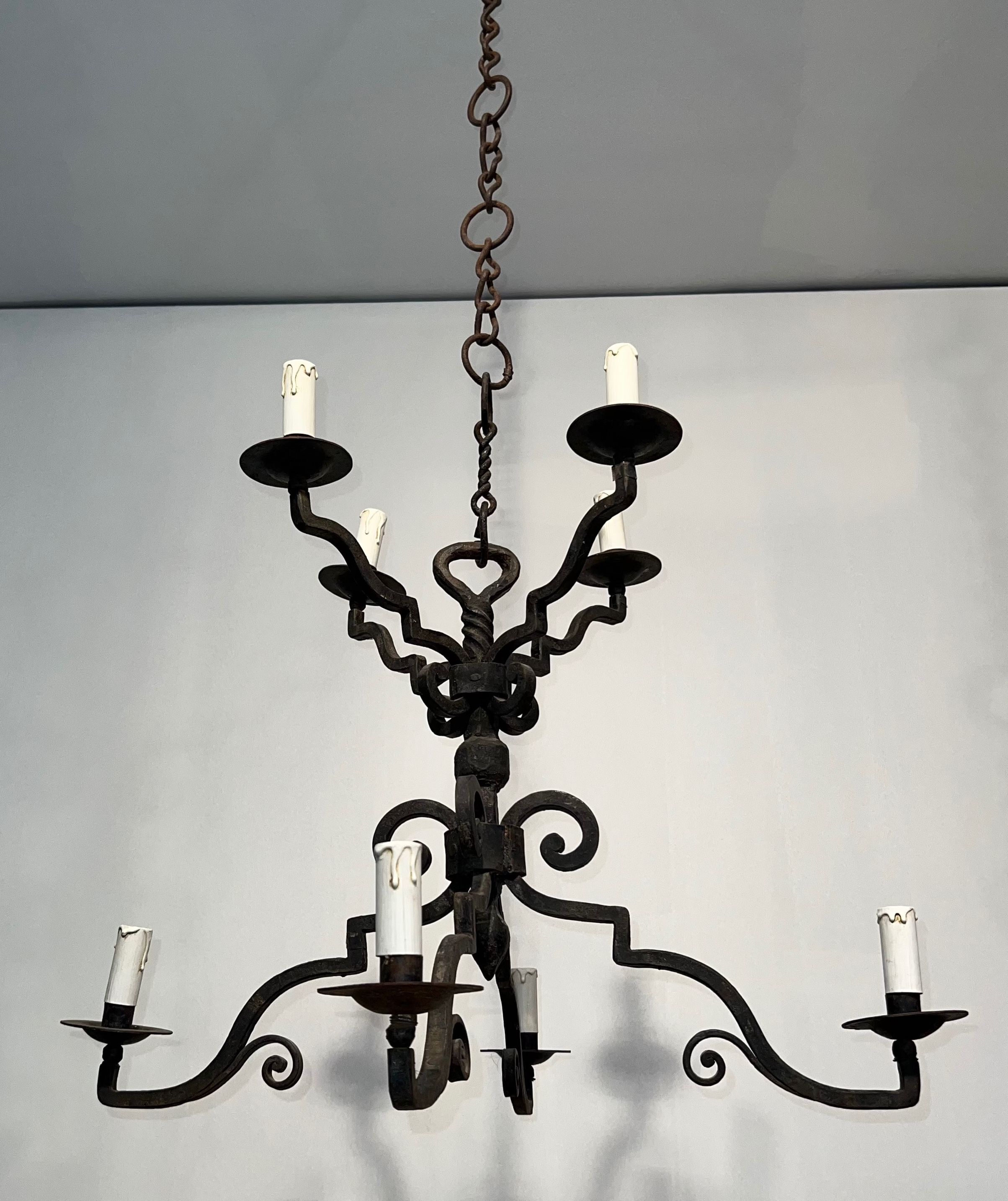 Two-tiered wrought iron chandelier with eight light arms in Gothic style.
