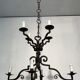 Two-tiered wrought iron chandelier with eight light arms in Gothic style.