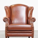 Correct, comfortable, luxurious English-style wingback armchair made of cognac-colored cow leather