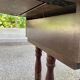 Small drop-leaf side table in English style with leather top & drawer.