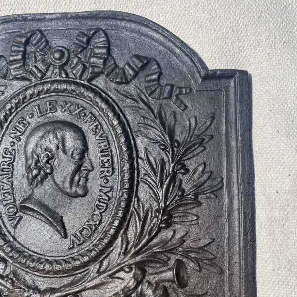 Plaque de cheminée ancienne en fonte , ruban, laurier, portrait de Voltaire