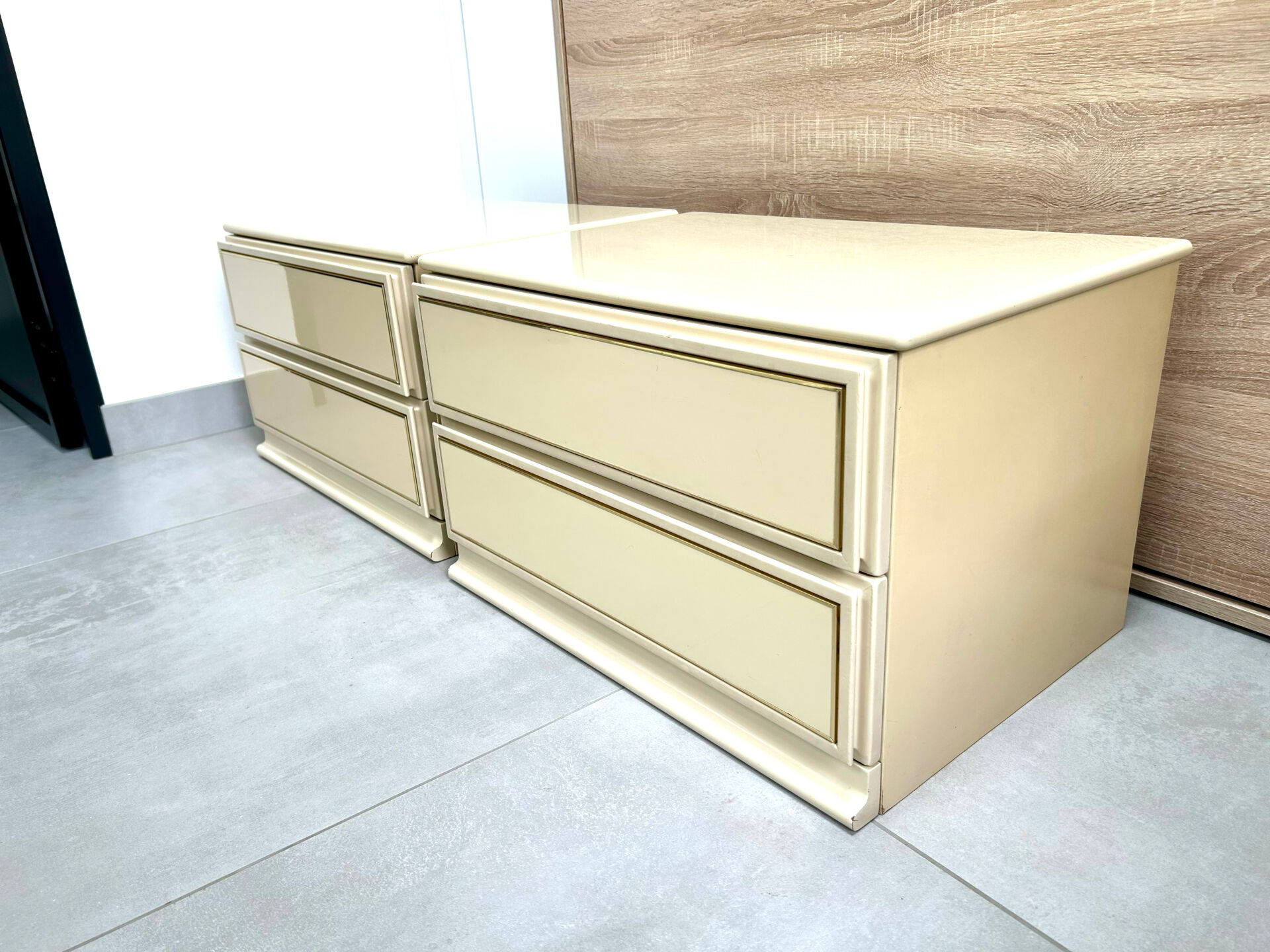 Pair of bedside tables with 2 drawers, glossy cream and gold, 1980.