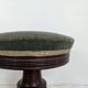 Green velvet piano stool with a turned leg.