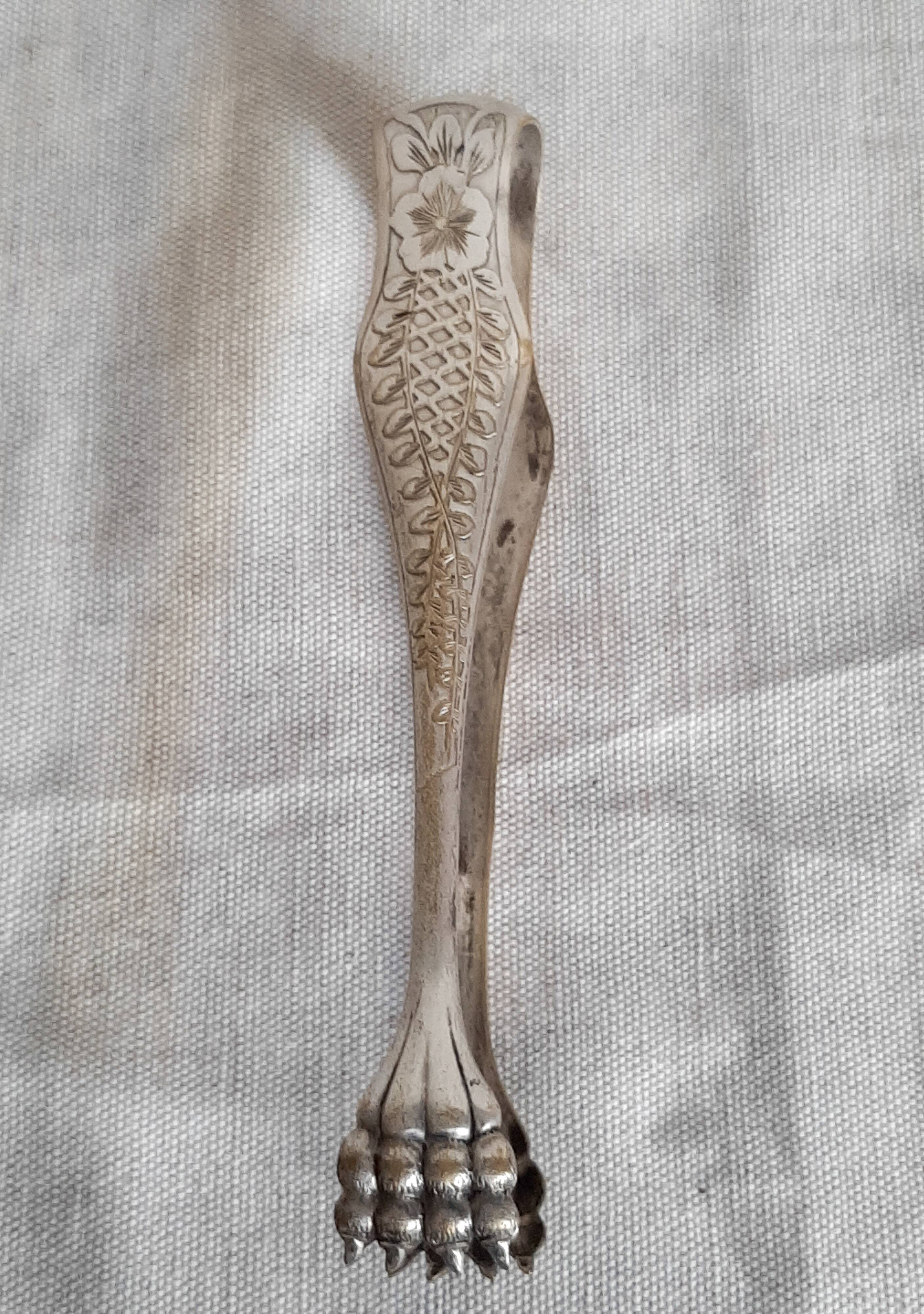 Antique silver-plated sugar tongs with lion's paws.
