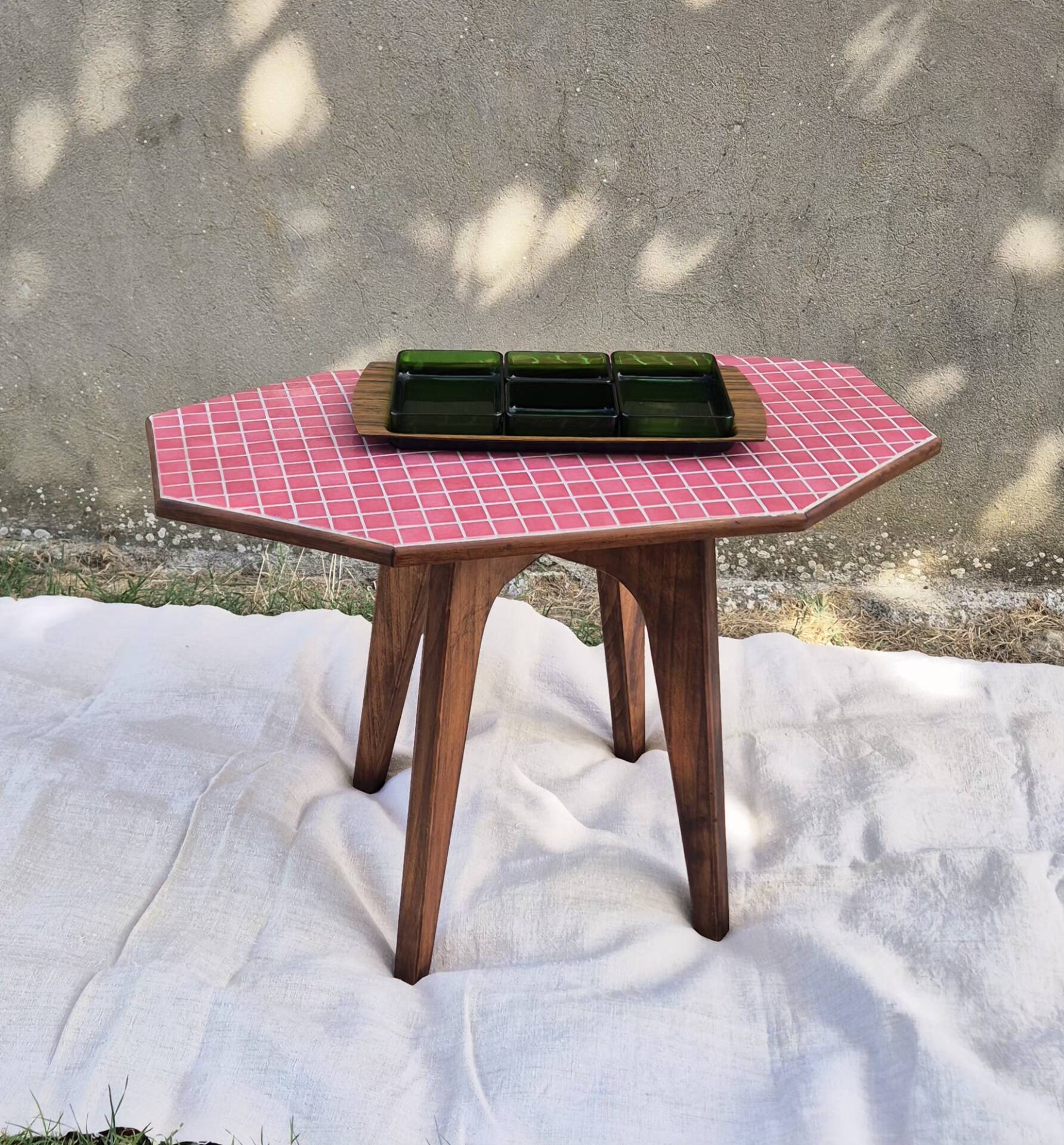 Small Scandinavian side table with wood and pink tiles, with tapered legs.