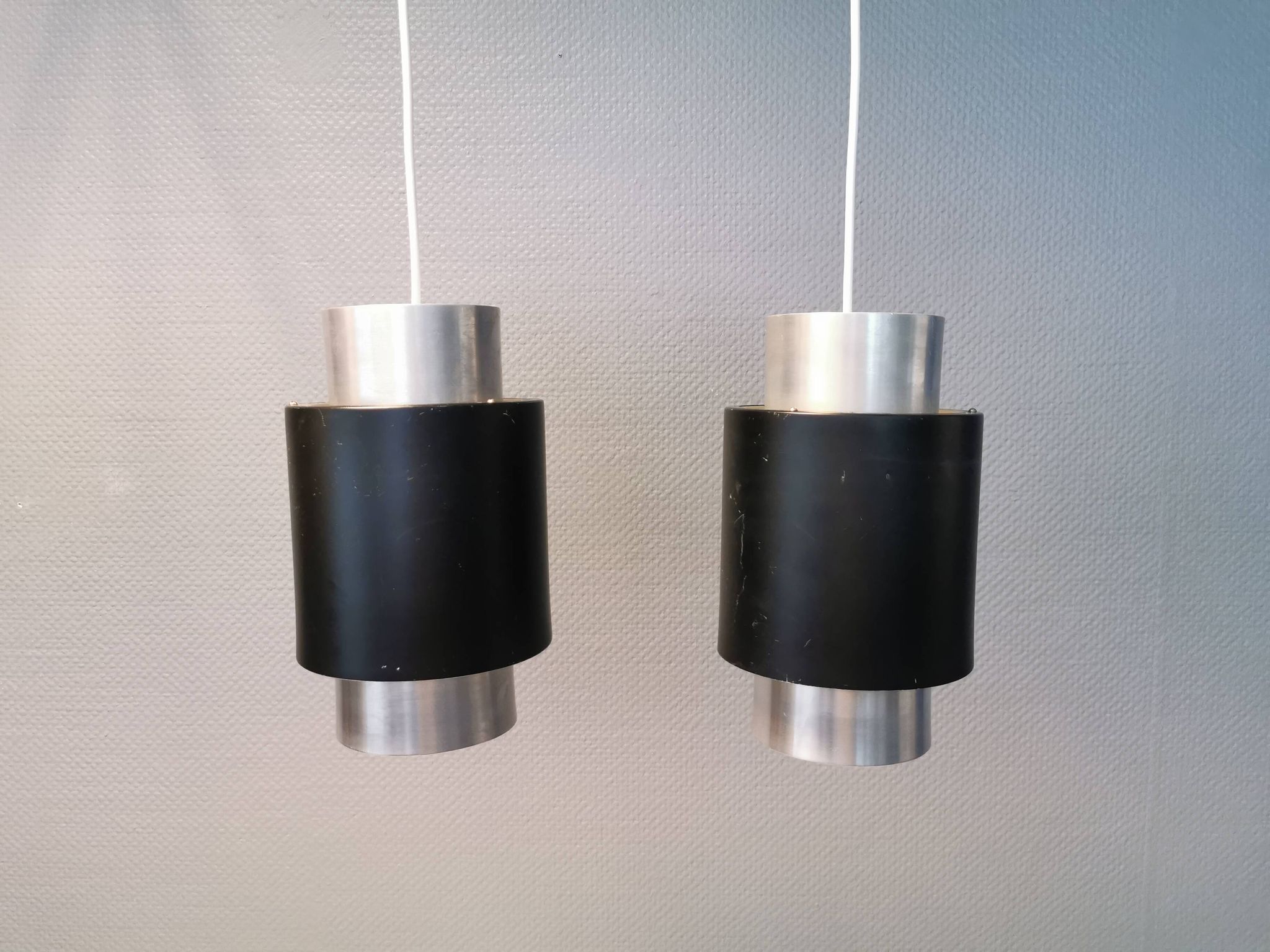 A set of beautiful cylinder shaped hanging lamps in silver color with black "ring" Danish 1970s.