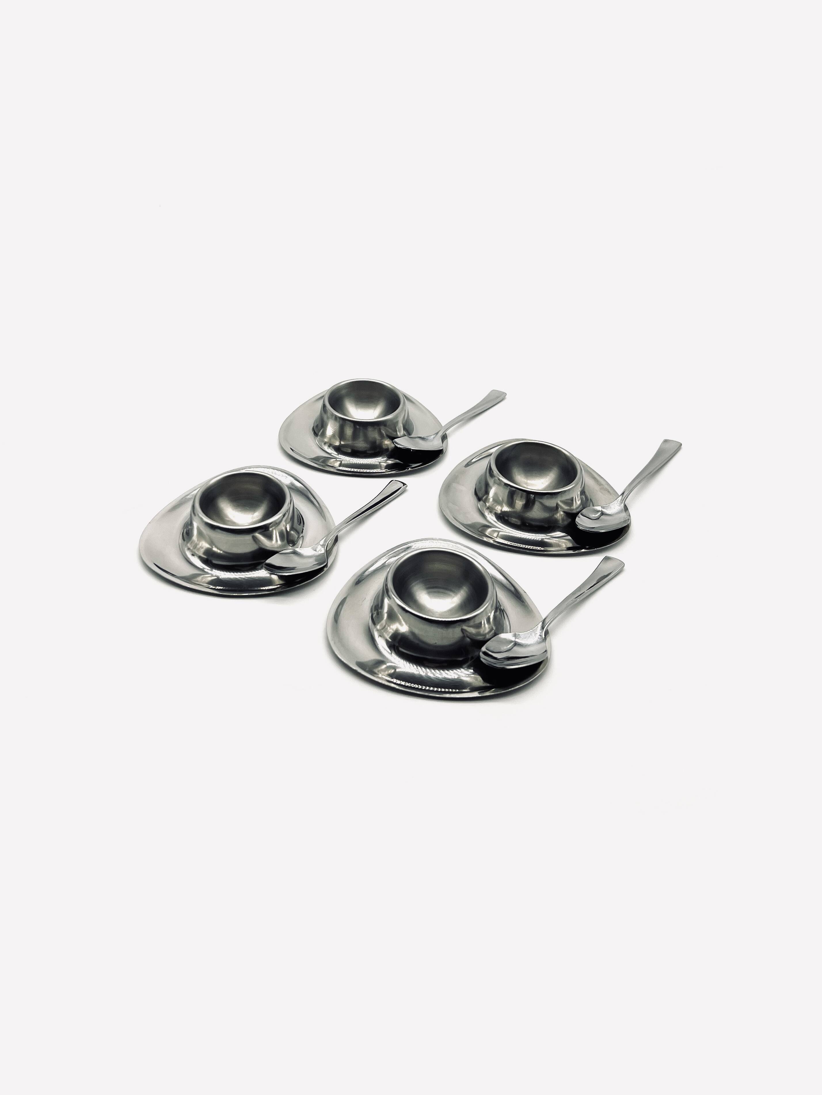 Four stainless steel egg cups and spoons
