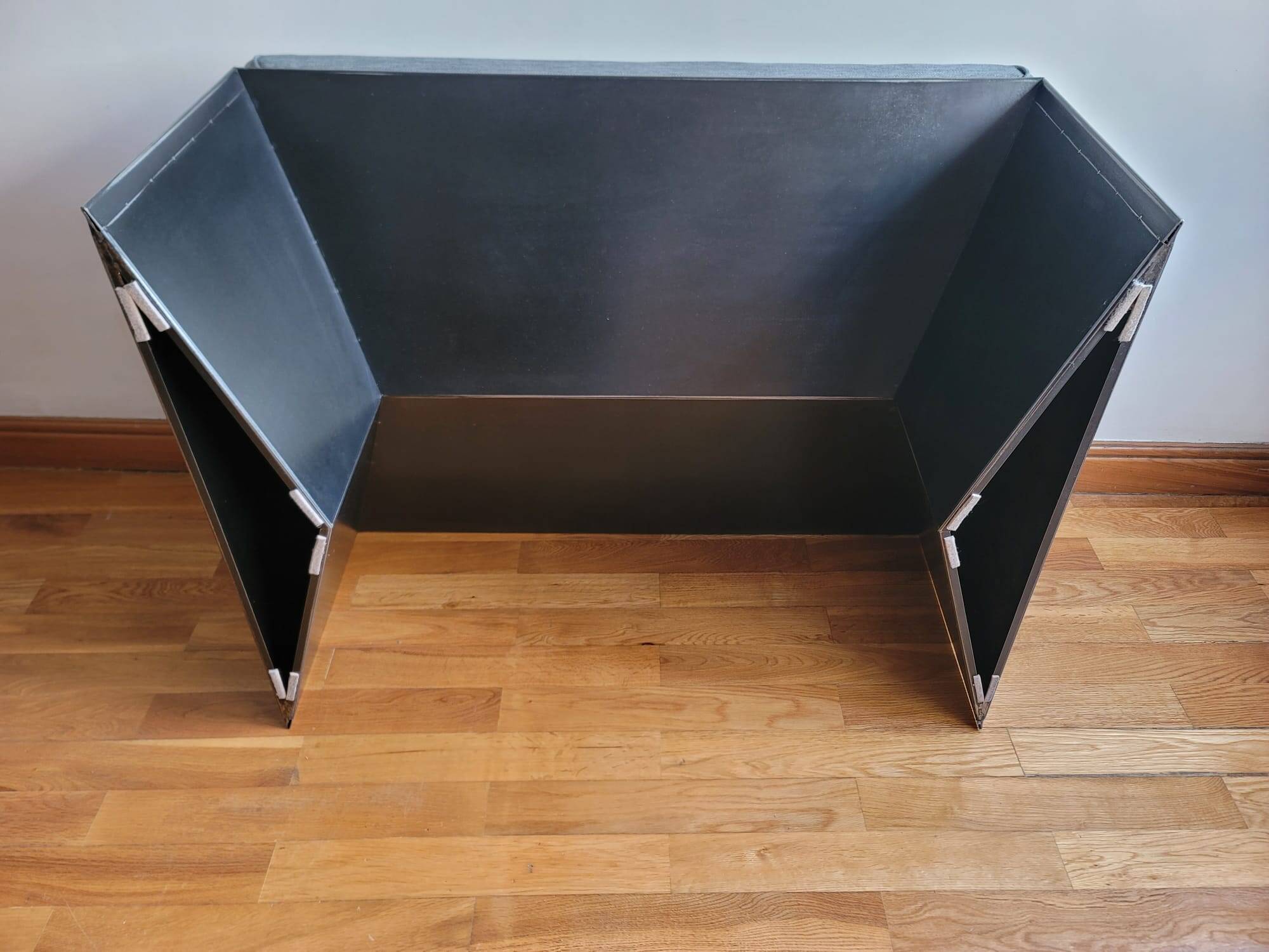 Minimalist/industrial coffee table with a black metal frame and a grey fabric top.