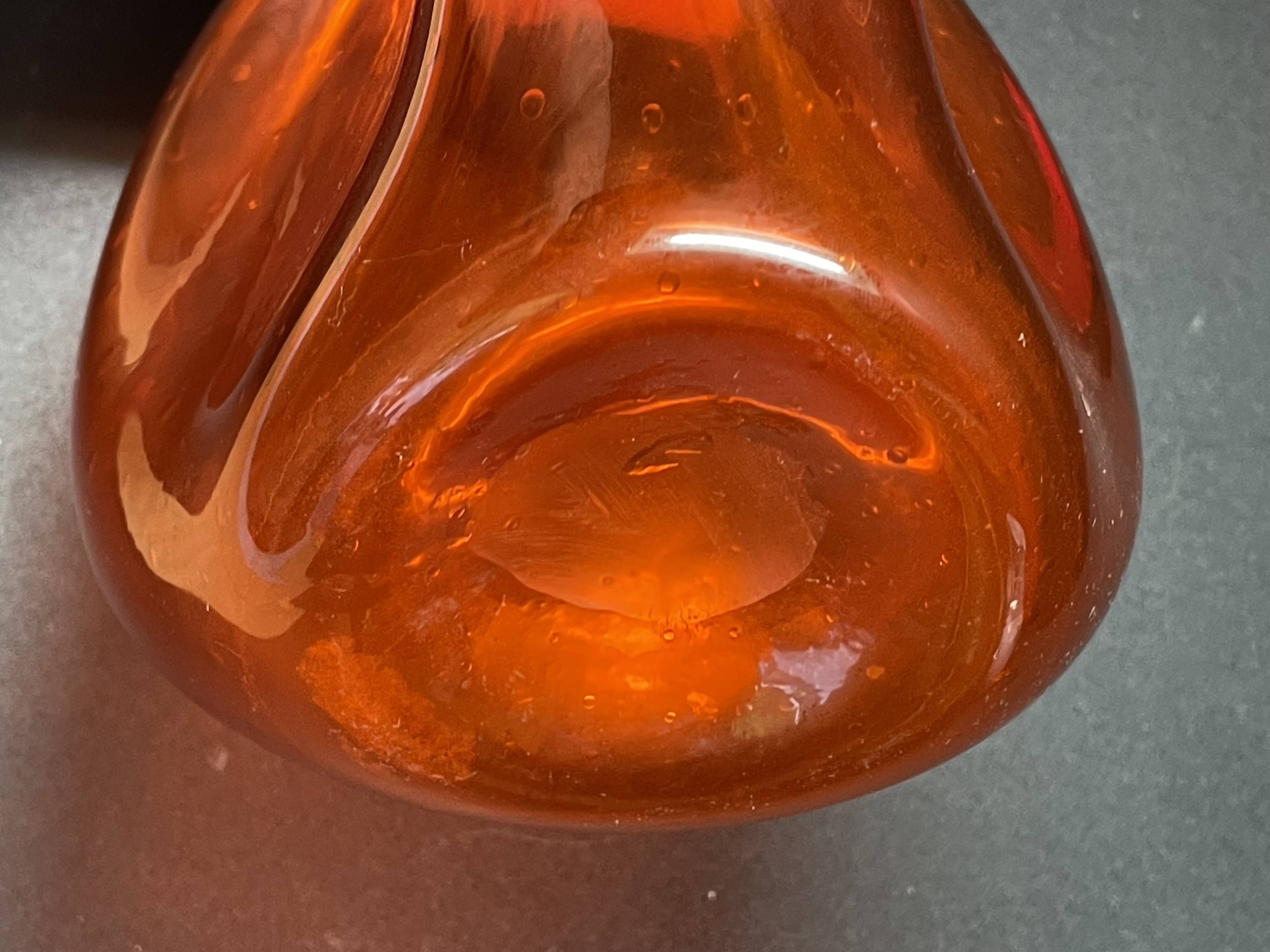 Orange bubbled glass bottle with curved body, circa 1970
