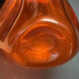 Orange bubbled glass bottle with curved body, circa 1970