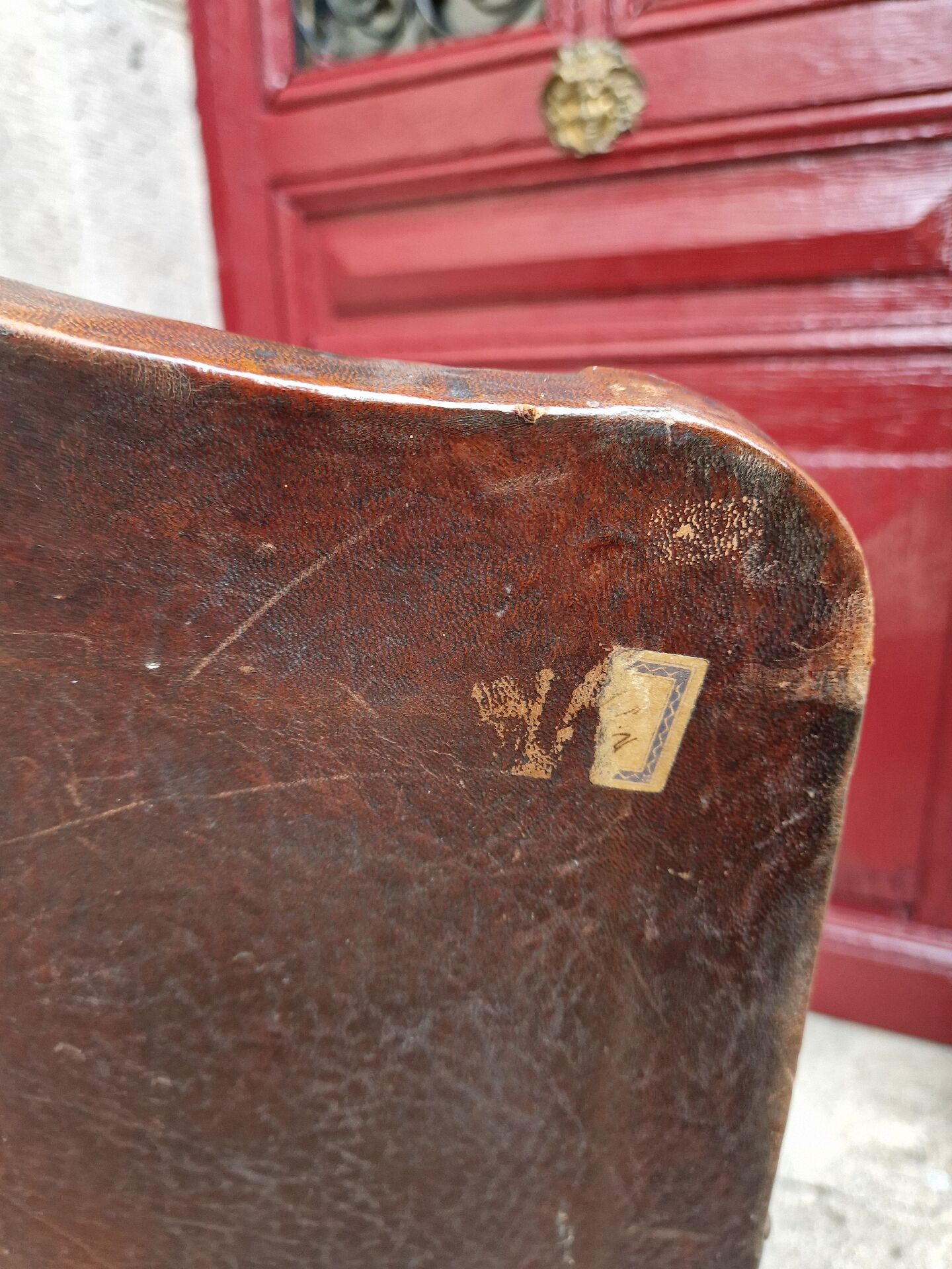 Antique club chair in patinated brown leather, early 20th century English style.
