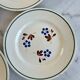 Set of 4 small flat plates with floral designs.
