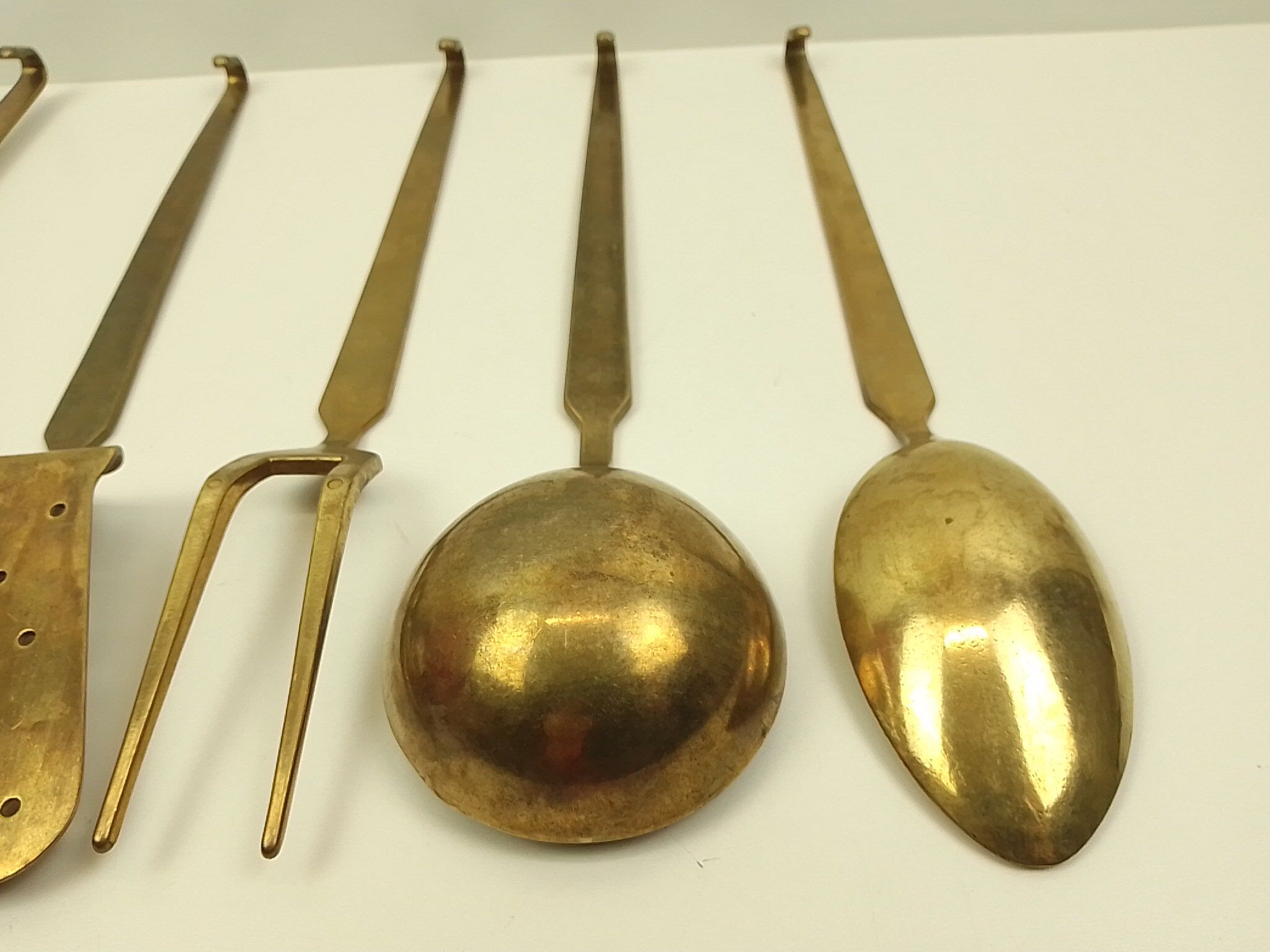 5 kitchen utensils and a brass wall mount
