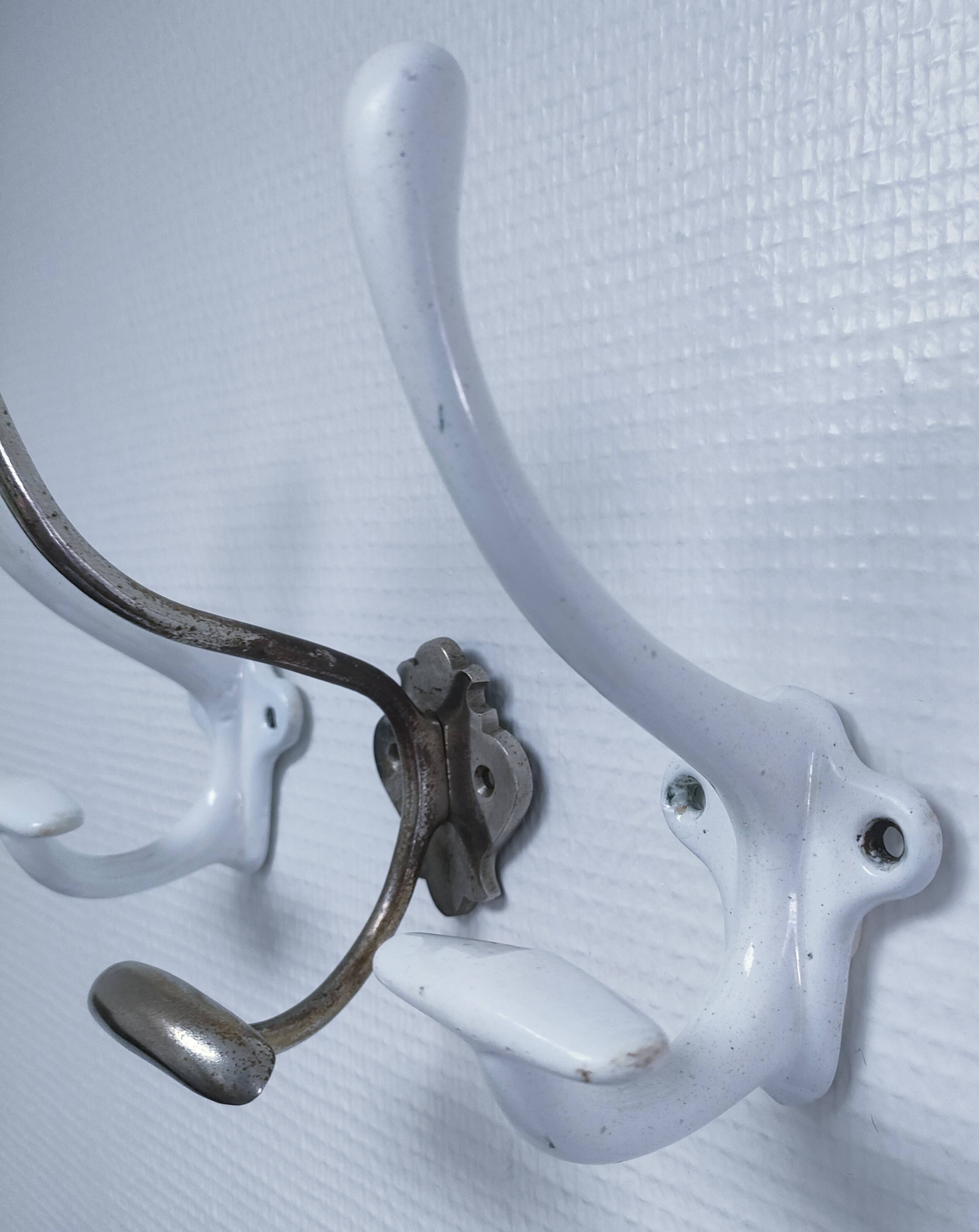 Three enameled cast iron coat hooks and vintage patina metal