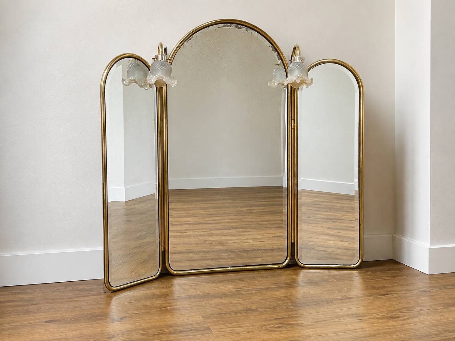Vintage triptych mirror in brass with wall lights.