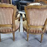 A pair of gilded wooden armchairs in the Louis XVI style.
