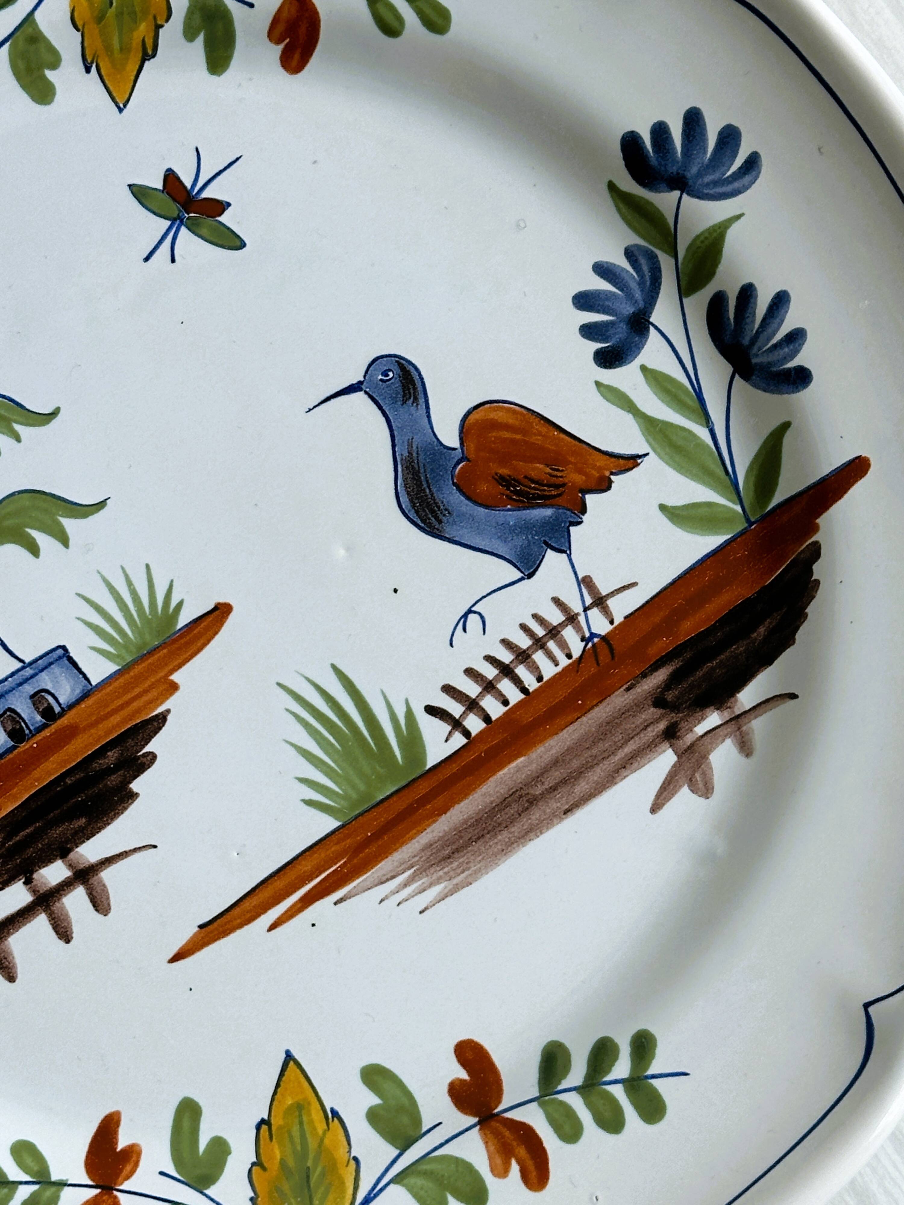 Hand-painted earthenware plate with landscape and bird decoration.