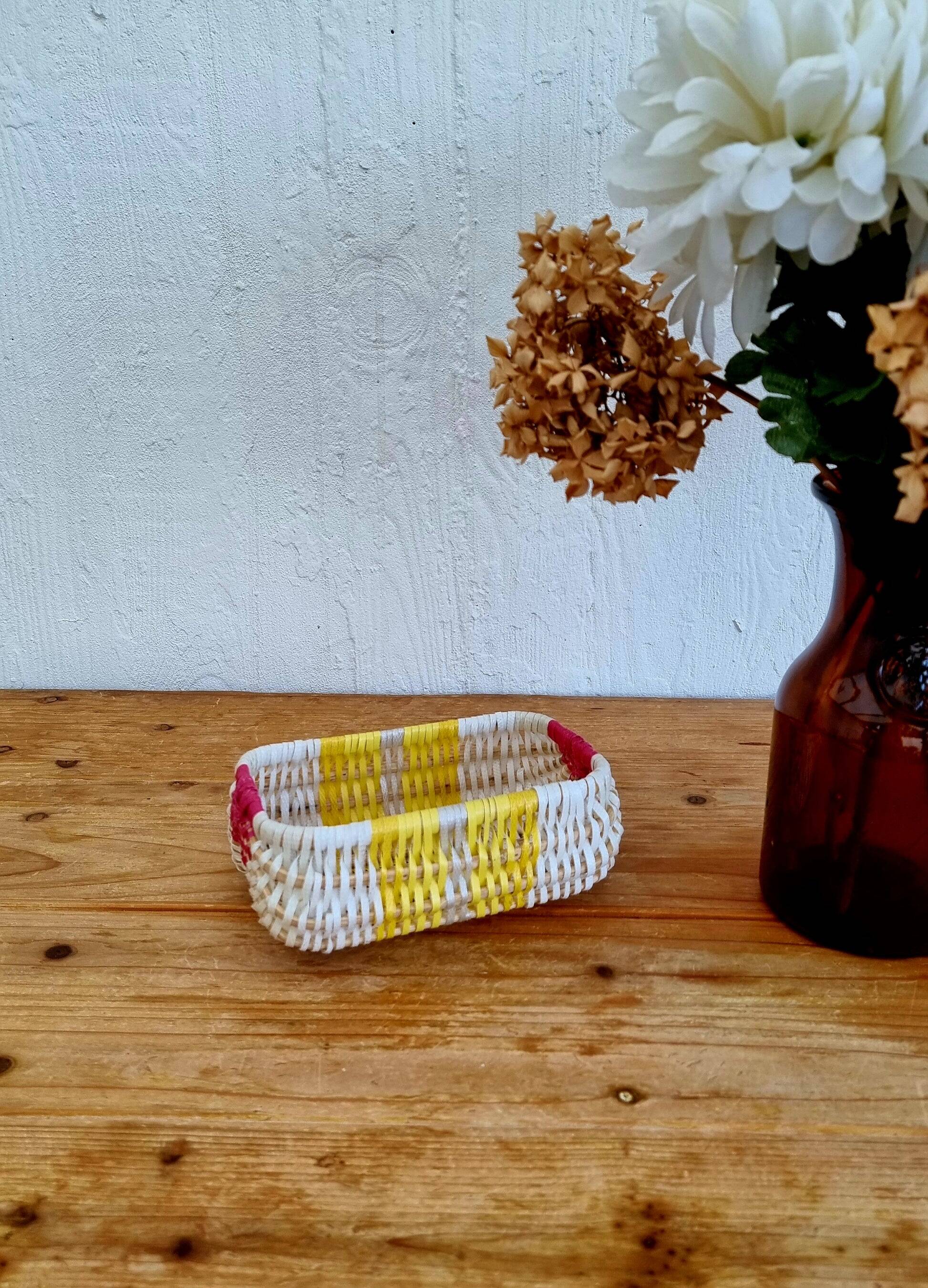 Vintage woven basket in yellow, white, and pink plastic.