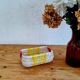 Vintage woven basket in yellow, white, and pink plastic.