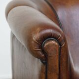 Fauteuil club en cuir de mouton foncé avec passepoil noir