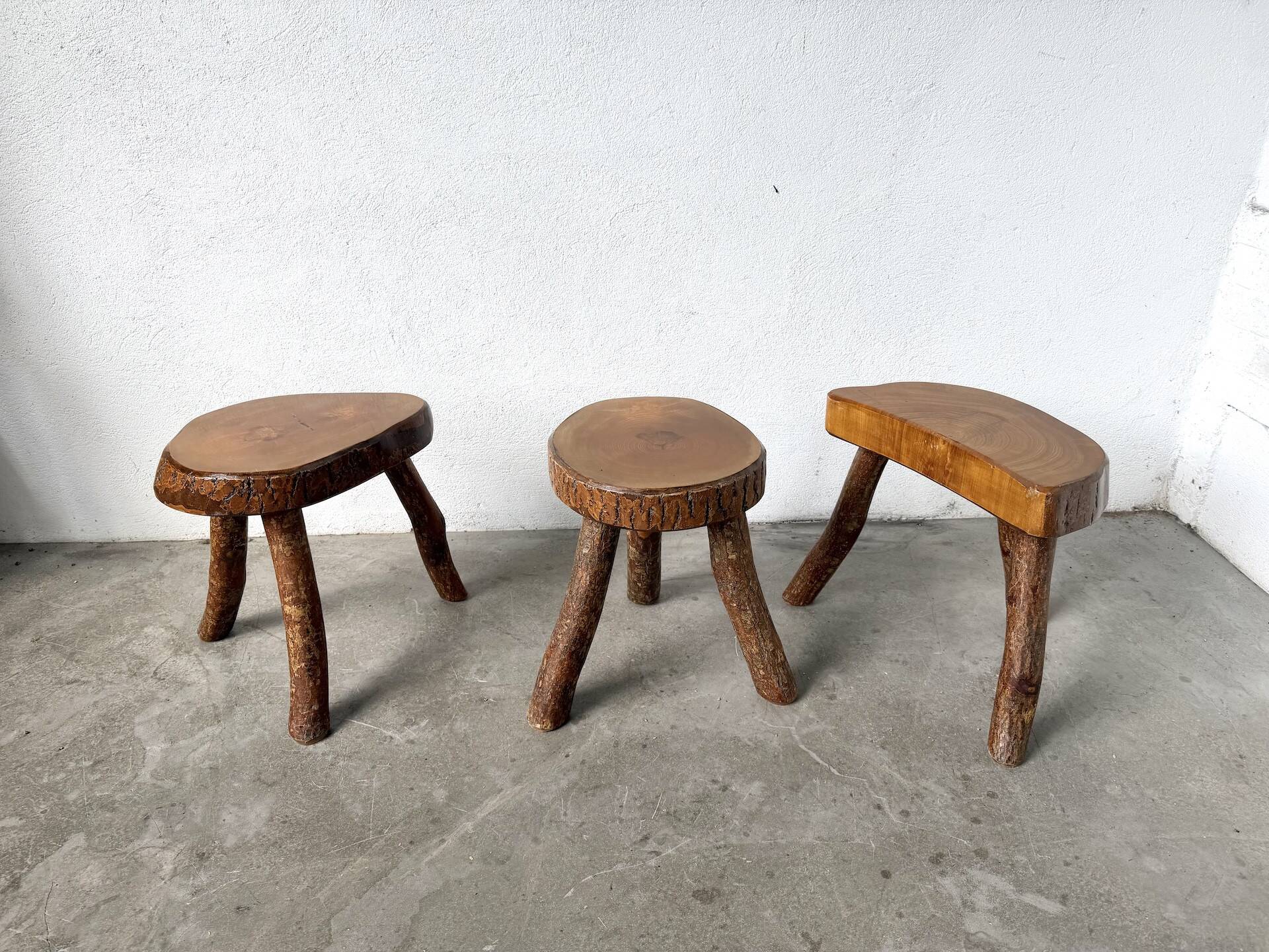 Set of three rustic solid wood tripod stools.