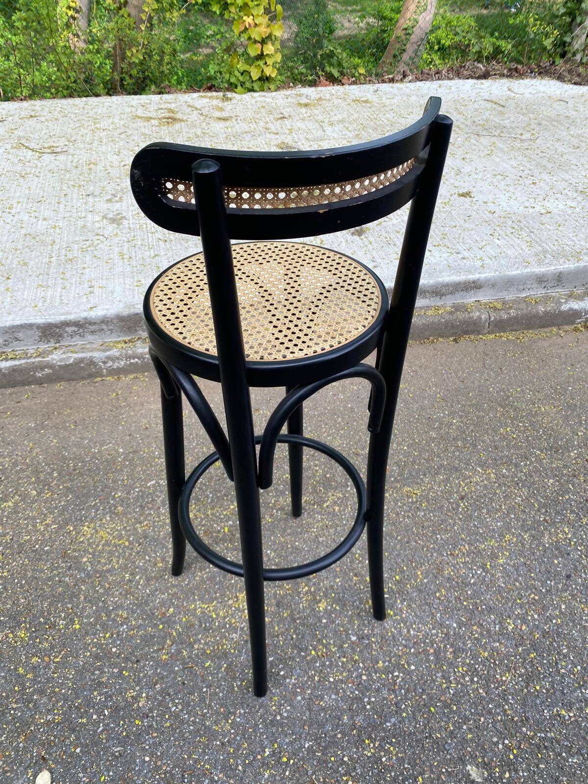 High bistro bar stool in curved black wood with a cane backrest.