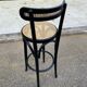 High bistro bar stool in curved black wood with a cane backrest.