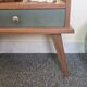 Renovated vintage bedside table in wood, with tapered legs – Matt green & gold background