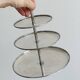 Vintage three-tiered serving stand in patinated silver metal.