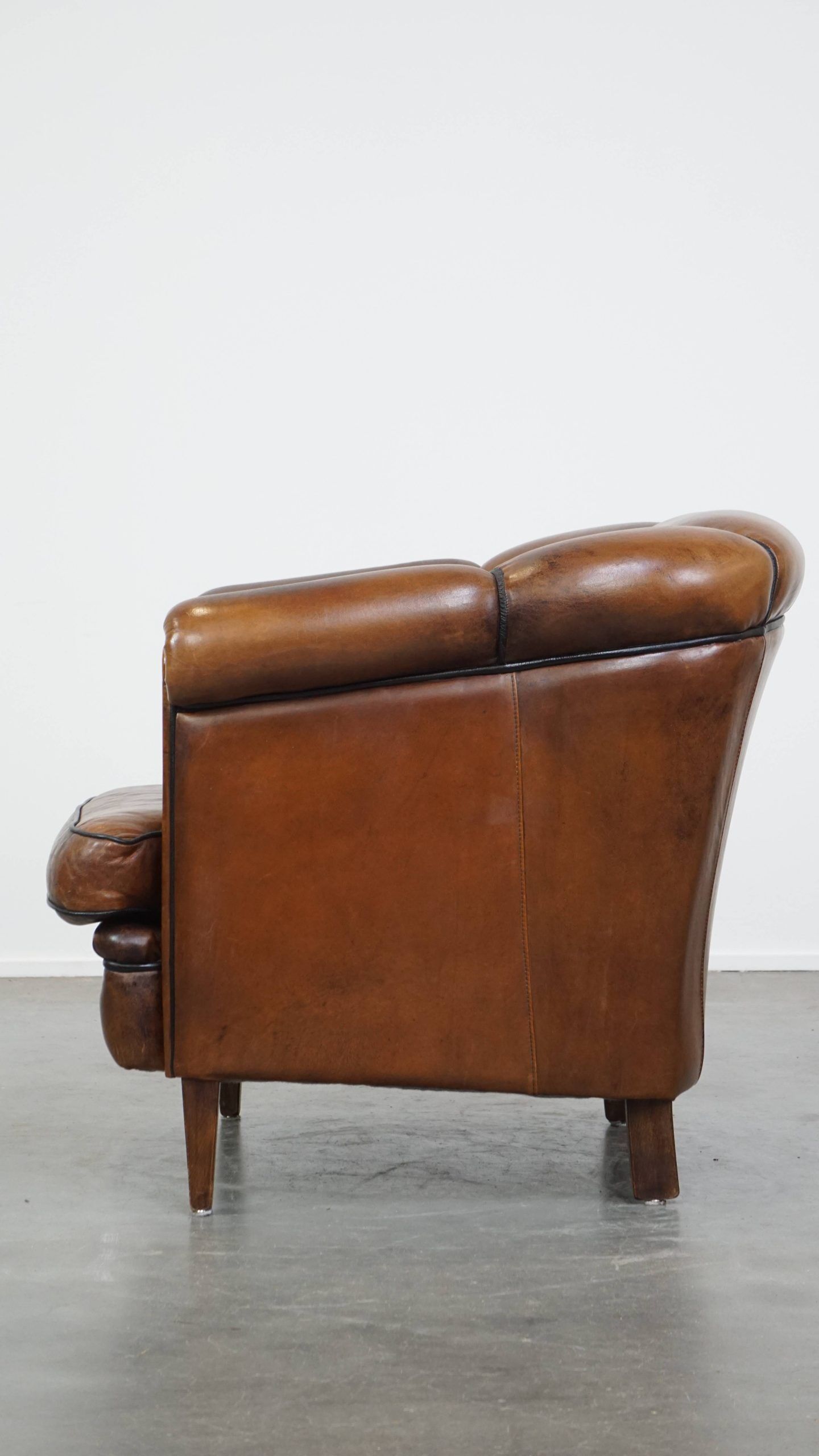 Unique vintage cognac-coloured leather club armchair with black piping
